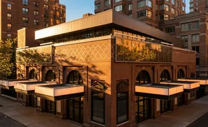 Brick building with modern glass upper floors and illuminated awnings over entrances.