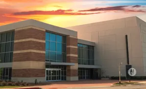 A modern building with brick and tan accents under a colorful sunset sky.