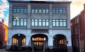 A historic, gray stone building with large windows and arched doorways.