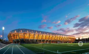 Modern stadium at dusk with a unique, curved, illuminated facade.