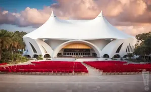 An outdoor amphitheater with a white tent-like roof and rows of red seats.