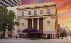 A historic theater with a purple marquee on a street with a dramatic sunset sky.