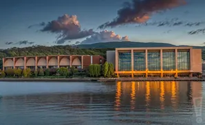 Modern buildings with large windows reflect light on the water at sunset.