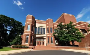 A large brick building with tall windows and a grand entrance on a sunny day.