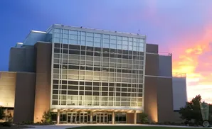 Modern building with a glass facade against a vibrant sunset sky.
