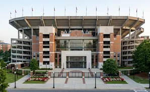 Exterior view of a large brick stadium with tiered seating and a central entrance.