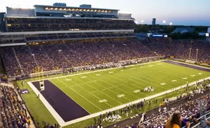 A football stadium filled with purple-clad fans at dusk.