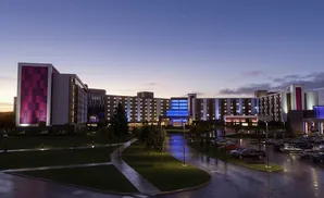 A modern hotel at dusk with purple and blue lighting on its facade.