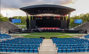 Outdoor amphitheater with a stage, seating, and screens.