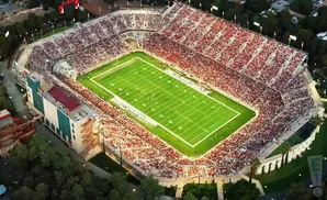 Aerial view of a crowded football stadium with a green field and red-seated stands.
