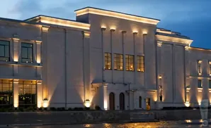 A lit, modern building with large windows, lit at dusk.