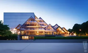 A modern building with a glass, pyramid-shaped roof at dusk.
