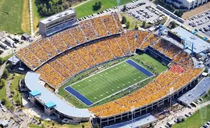 Aerial view of a packed football stadium with yellow-clad fans and a green field.