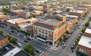 Aerial view of a downtown street with brick buildings, a theater, and parked cars.