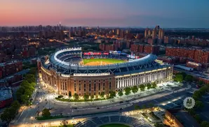 Aerial view of Yankee Stadium at dusk with surrounding city skyline.