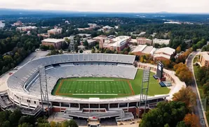 Aerial view of a football stadium surrounded by university buildings and autumn trees.