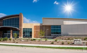 Modern building with stone accents and large windows under a bright sun and blue sky.