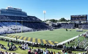 A football stadium filled with fans under a bright blue sky.