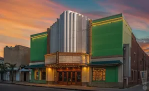 Art deco theater with green facade and marquee at sunset.