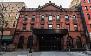 Exterior of a red brick building with arched windows and an entrance canopy.