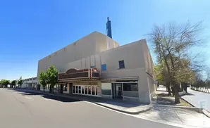 Exterior of an old movie theater with a marquee and adjacent storefronts.