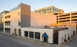 Modern beige and grey buildings at sunset, with a multi-level parking garage in the background.