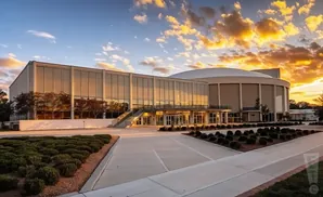 Exterior view of a modern building with a glass facade, reflecting a dramatic sunset sky.