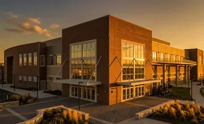 Modern brick building with large windows reflects warm sunset light.