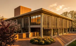 A modern brick building with patterned screens on its facade, bathed in golden sunset light.
