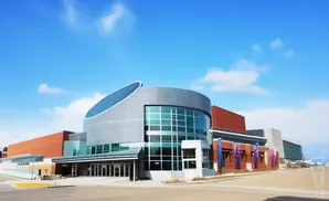 A modern building with a curved, silver facade and a large glass window.