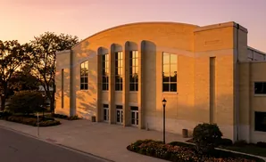 Golden hour light illuminates a yellow brick building with arched windows and a curved roof.