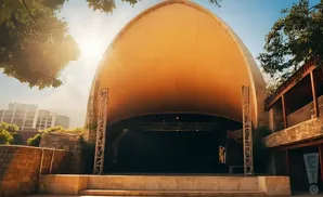 Outdoor amphitheater stage with a large, curved, orange canopy.