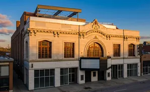 Exterior of a white-tiled building with arched windows and a rooftop deck.
