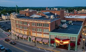 Aerial view of a town square with a brick building featuring a theater marquee and striped awnings.