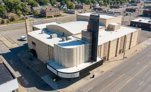 Aerial view of a beige brick building with a curved marquee and a tall black and red tower.