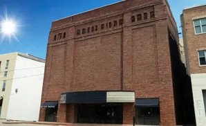 Exterior of a red brick building with dark awnings over storefronts.