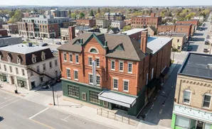 Aerial view of a brick building with a green facade and a marquee, in a town with other buildings and streets.