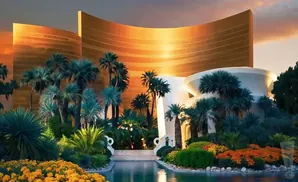 Golden resort building with palm trees and lush gardens at sunset.