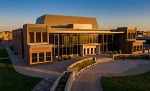 Modern brick building with large windows and sloped roof, at sunset.