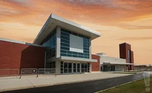 Modern brick and glass building with an orange sky.