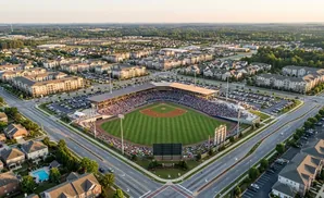 Aerial view of a baseball stadium filled with fans, surrounded by residential buildings and parking lots.