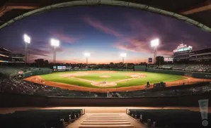 A baseball stadium at dusk, with bright lights illuminating the field and a colorful sky.