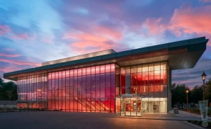 a high-resolution, ultra-realistic digital photograph captures the exterior of the cain center for the arts in cornelius, north carolina, at dusk.the building features a striking modern architectural 