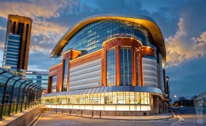 a hyper-realistic wide-angle aerial photograph of motorcity casino hotel in detroit, michigan, captured at sunset with golden light emphasizing the venue’s bold and curved modern design. 