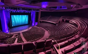 an interior picture of the pearl concert theater in las vegas, nevada. there is a big led screen with a blue light on stage. there are purple lights coming from stage.