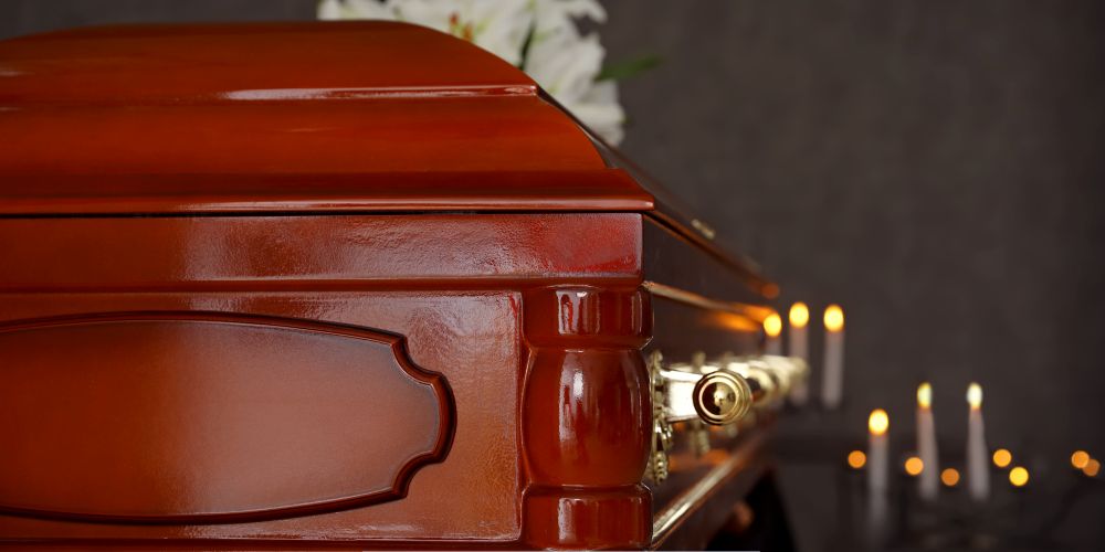 Close-up of a polished wooden casket with candlelight in the background at a Funeral Home and Cremations in Muskego, WI.