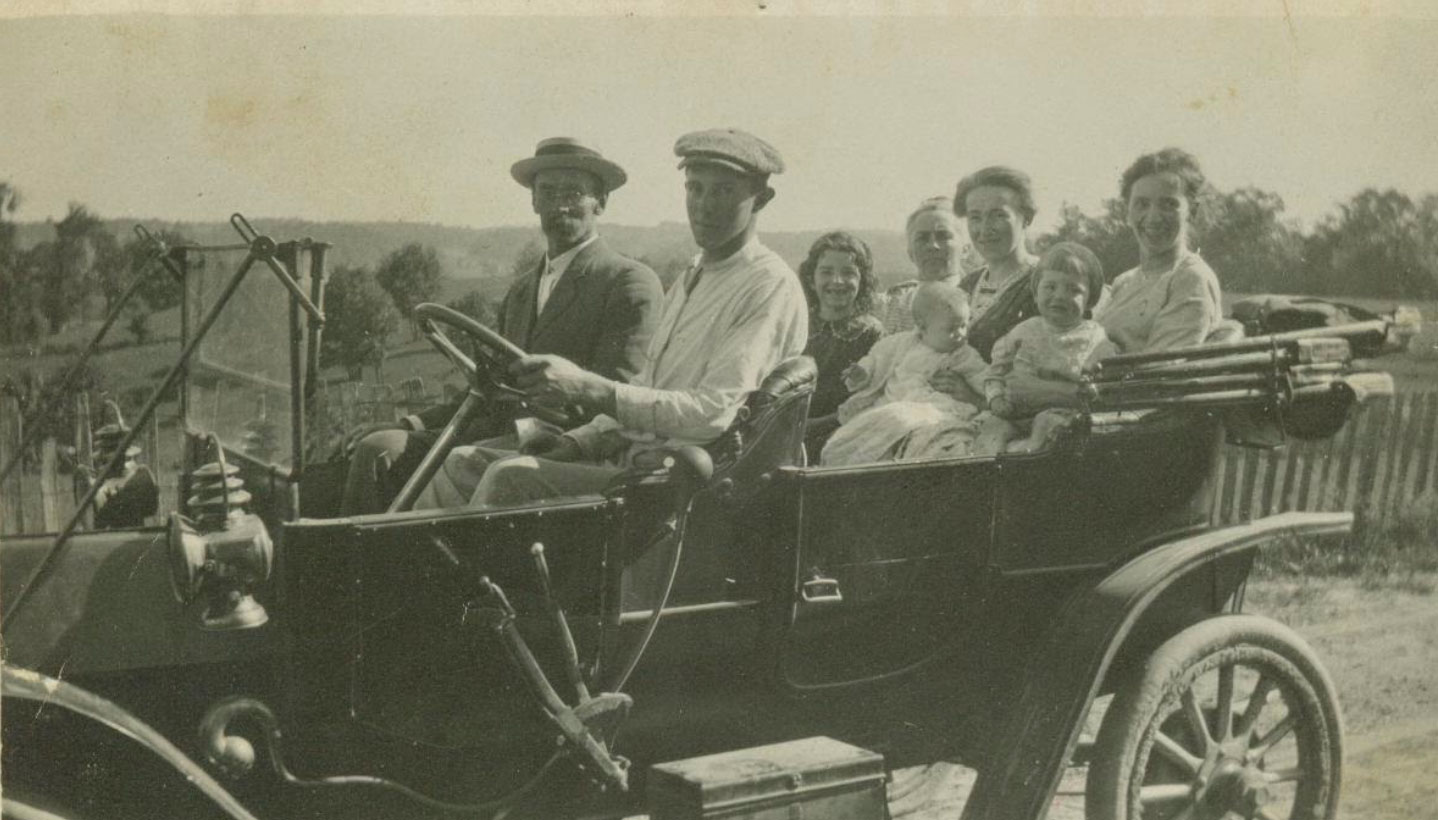 Ora Otis Snyder driving with his dad Henry Albert Snyder in the passenger seat, his sister Hazel Snyder laughing in the back seat.