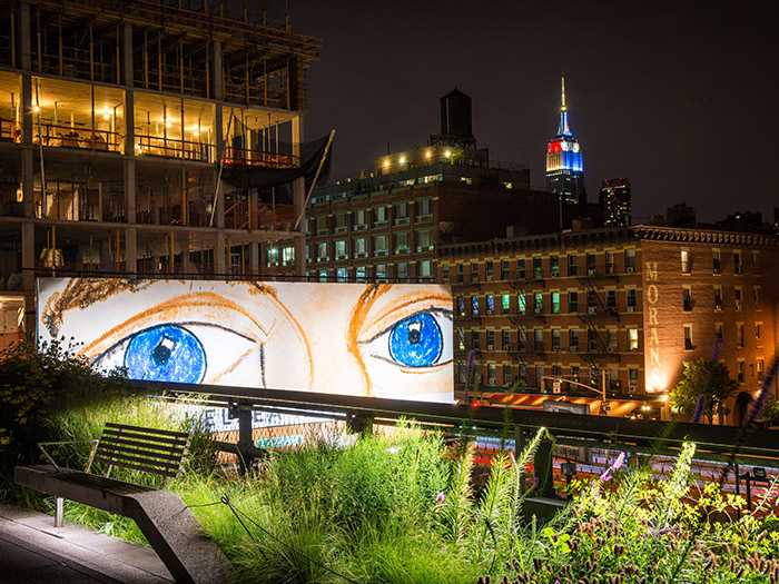 A pair of eyes on a neighboring billboard seem to watch over the High Line. Photo by Mike Tschappat