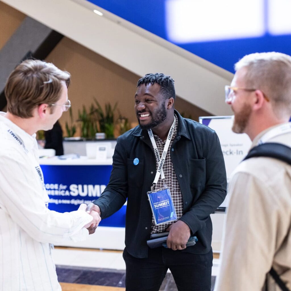Three Code for America Summit attendees greet each other smiling