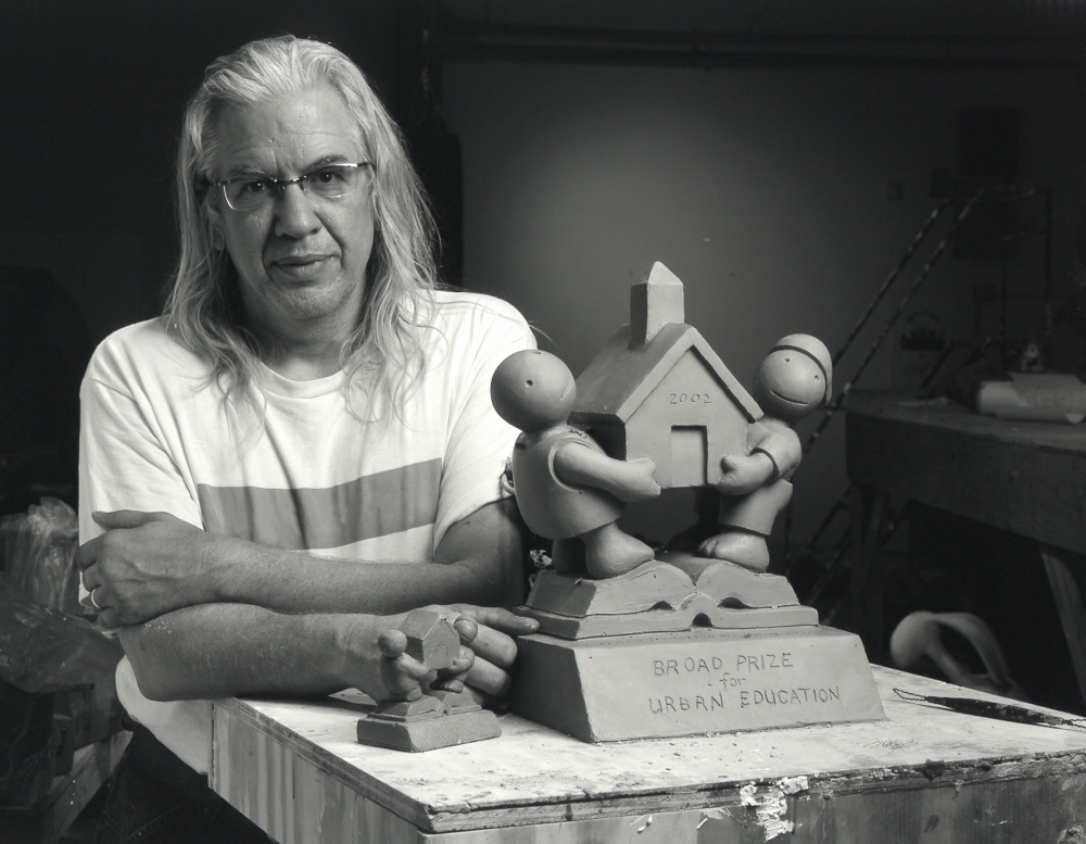 Black and white photographic portrait of Tom Otterness in his studio with model for Broad Prize for Urban Education